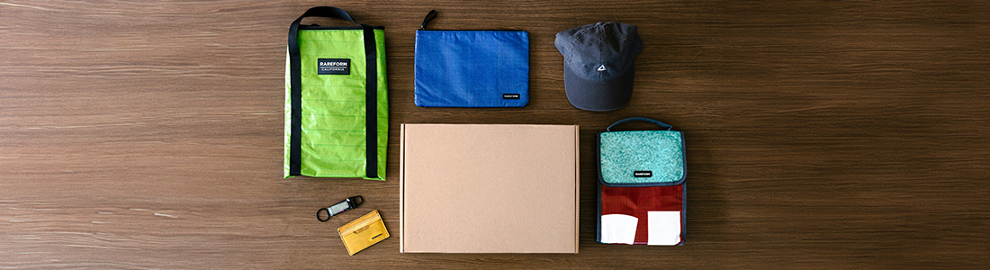 imagen knolling de un welcome pack formado por mochila, cartera, gorra y otros elementos de tela
